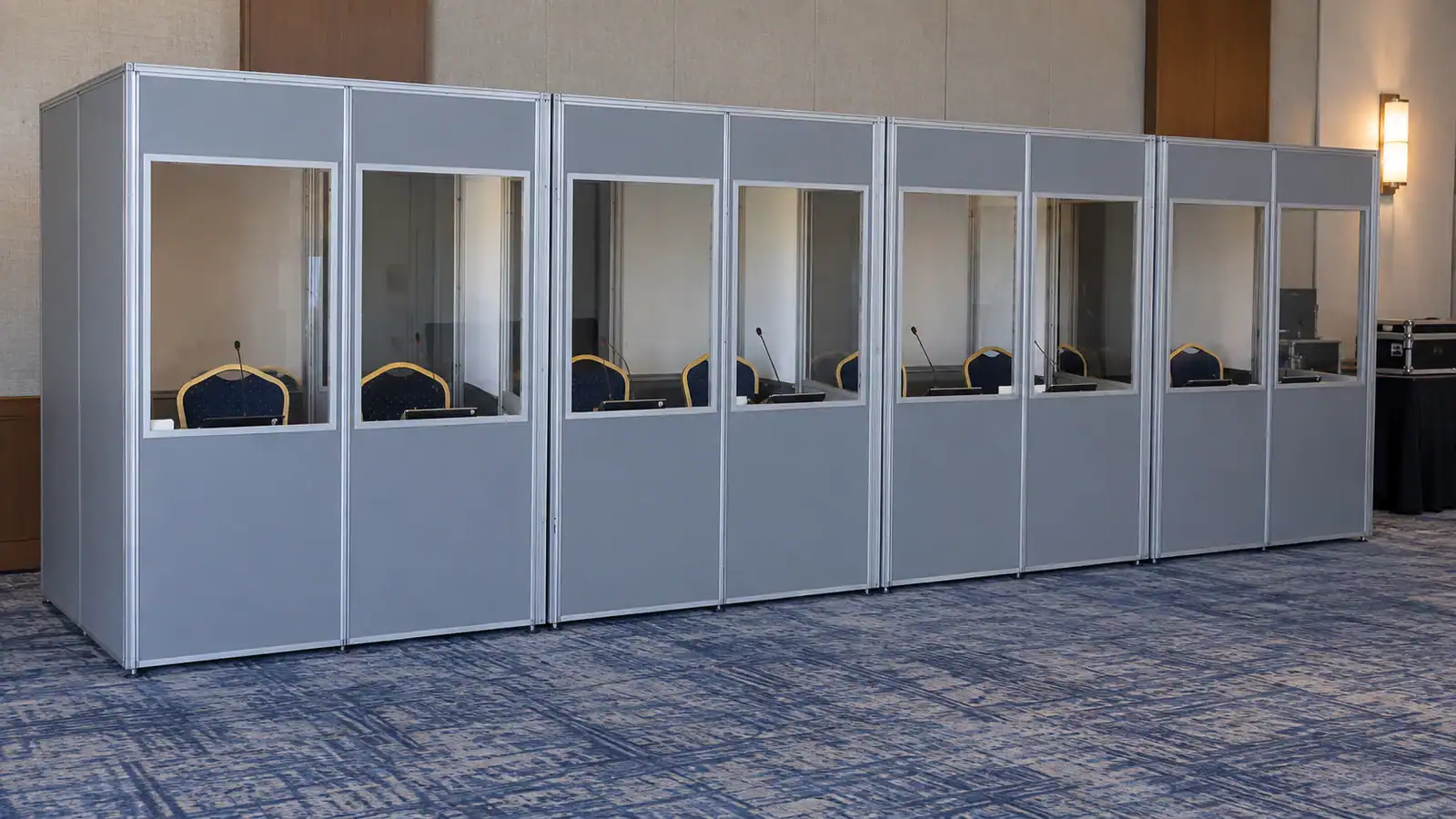 Modular simultaneous interpretation booths with grey panels, aluminium frames and individual viewing windows.